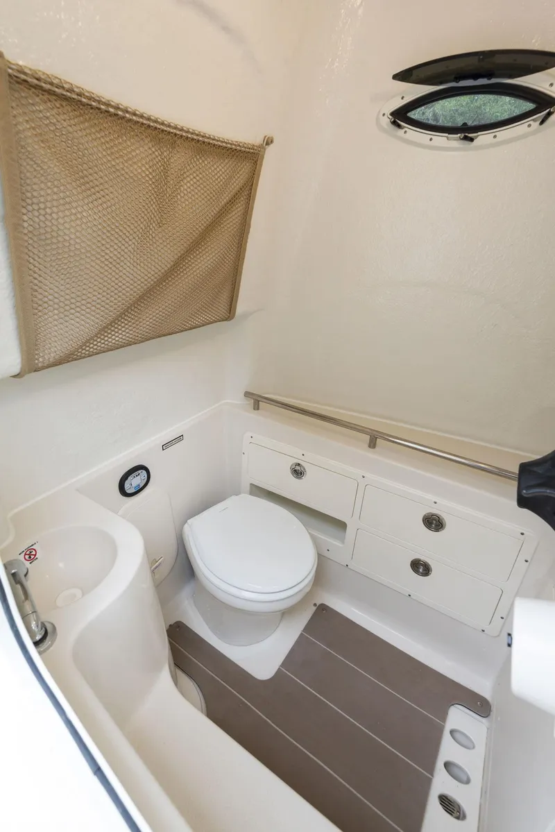 Slide: The Image of 2024 Sailfish 320 CC boat interior bathroom with toilet and storage. - 14