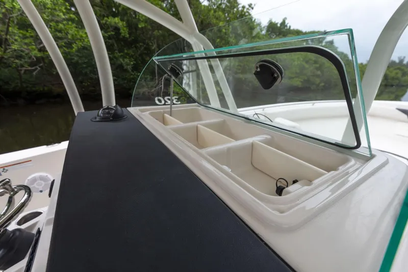 Slide: The Image of 2024 Sailfish 320 CC center console storage compartments with open glass lid. - 16