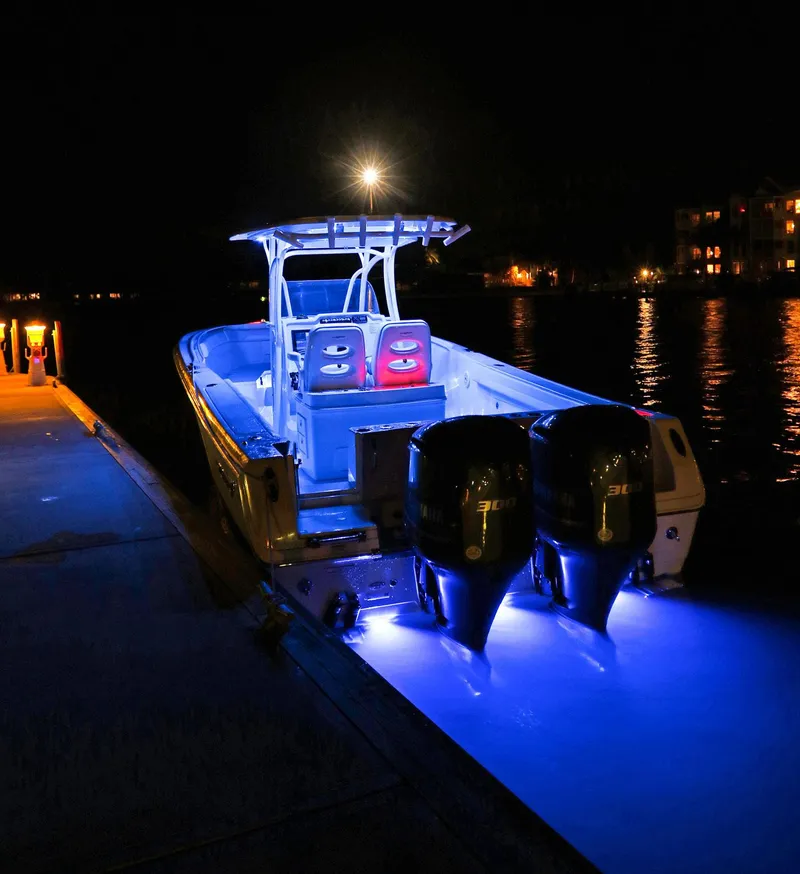 Slide: The Image of 2024 Sailfish 320 CC boat illuminated at night with blue underwater lights. - 22
