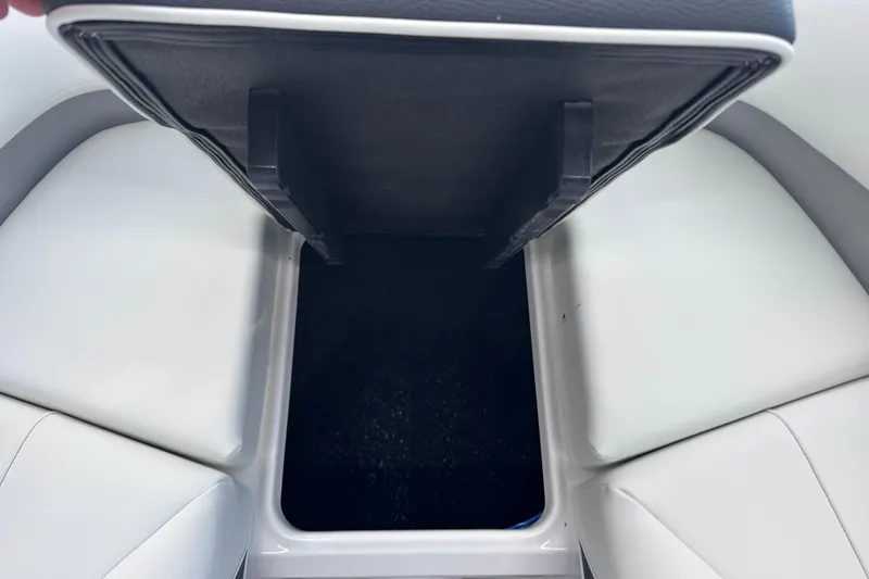 Slide: The Image of 2026 Regal LX6 boat storage compartment with open lid, showcasing sleek white seating. - 30