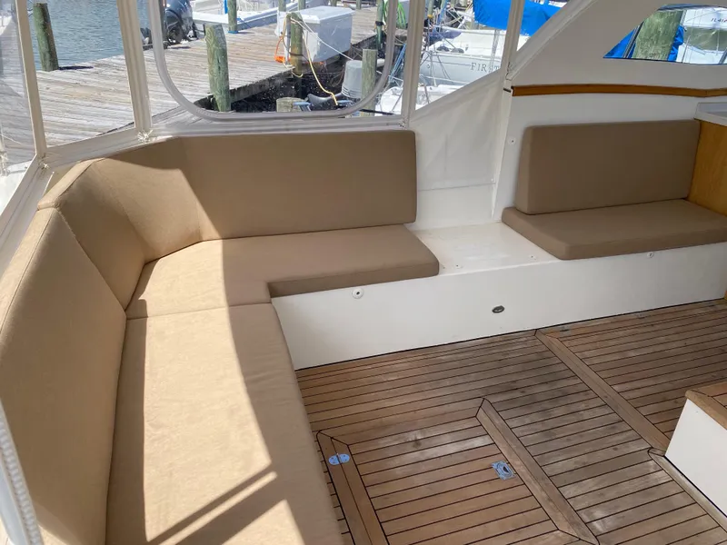 Slide: The Image of Interior seating area of a 2018 Custom Emerald Bay 36 boat with beige cushions and wooden flooring. - 15
