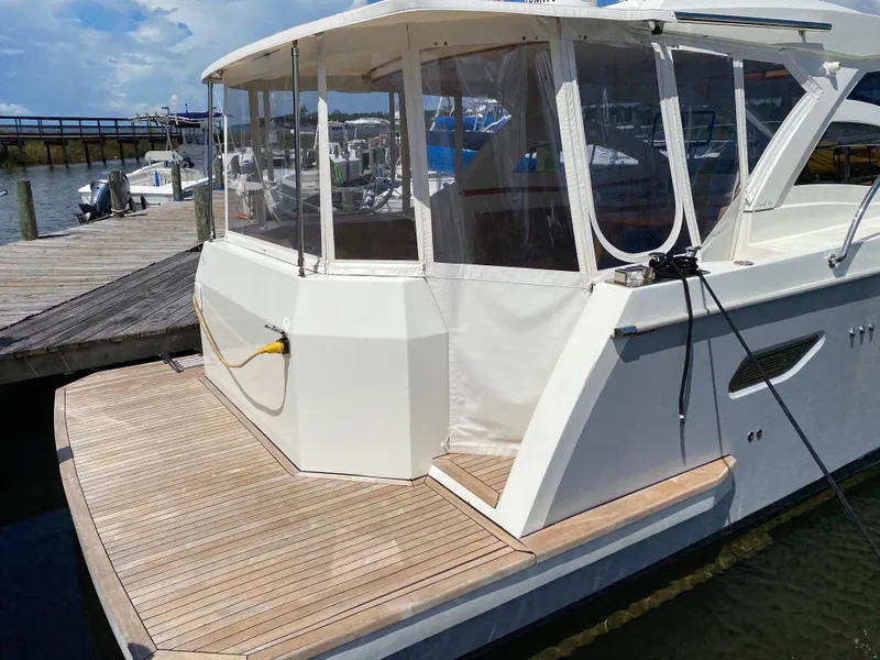 Slide: The Image of 2018 Custom Emerald Bay 36 docked, featuring a spacious rear deck and enclosed cabin. - 6