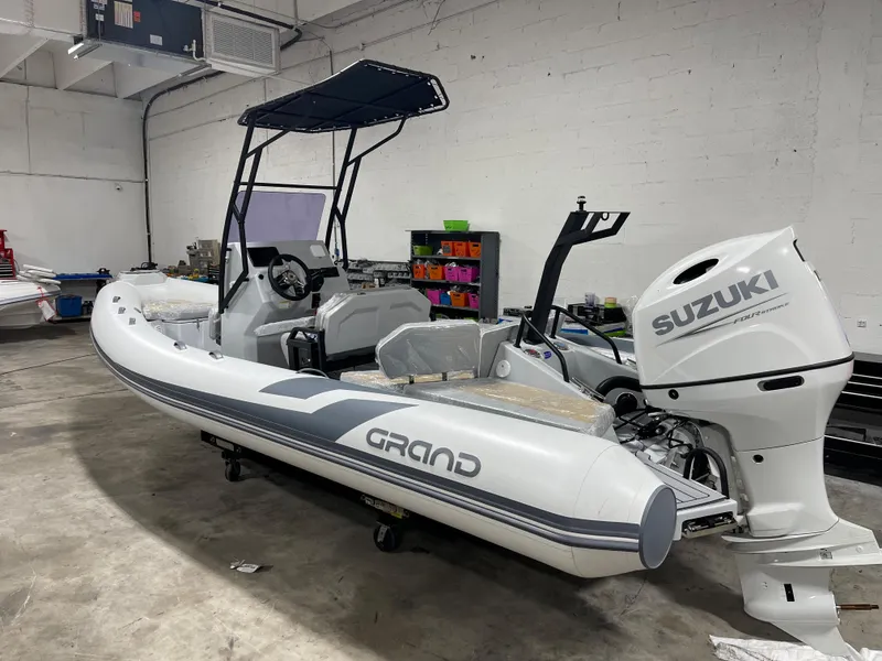 The Image of 2024 Grand D600 inflatable boat with Suzuki outboard motor in a garage. - 0