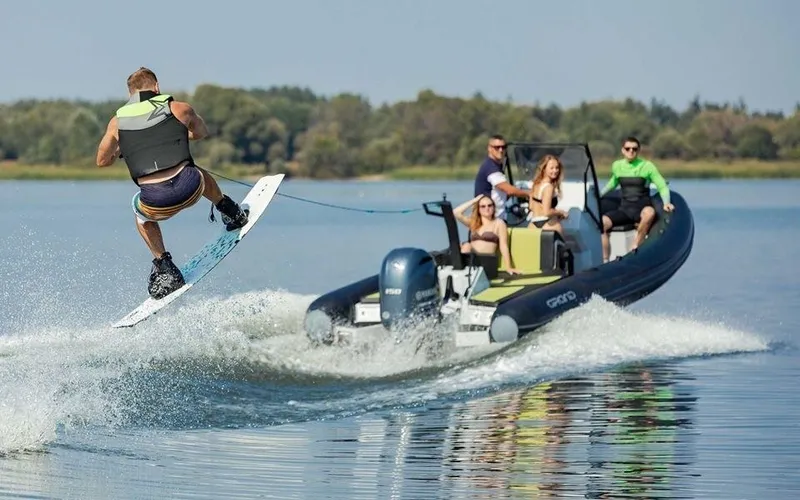 Slide: The Image of Wakeboarder jumps behind a 2024 Grand D600 boat on a lake. - 2