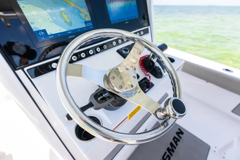 Slide: The Image of 2024 Sportsman Masters 247 Bay Boat helm with navigation screens and steering wheel. - 22