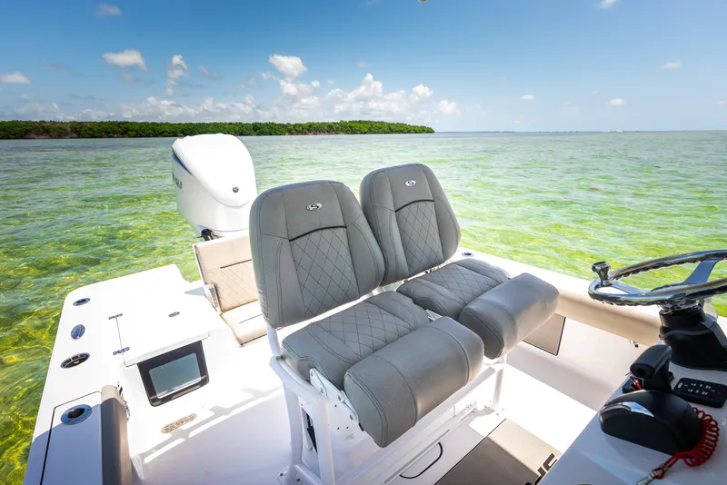 Slide: The Image of 2024 Sportsman Masters 247 Bay Boat interior with dual seats on clear water. - 7