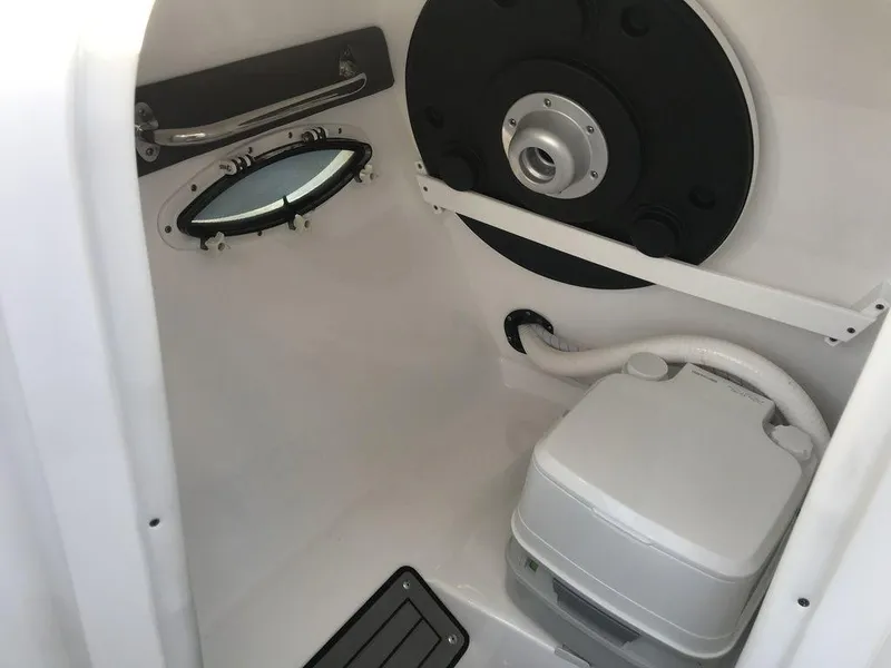 Slide: The Image of 2020 Rinker 29QX BR boat interior with a compact toilet and porthole. - 15