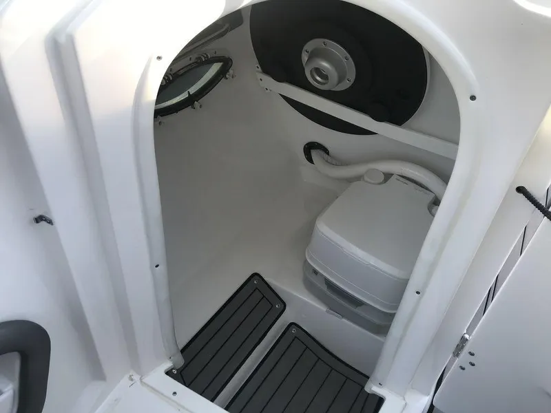 Slide: The Image of 2020 Rinker 29QX BR boat interior with compact toilet and porthole. - 4
