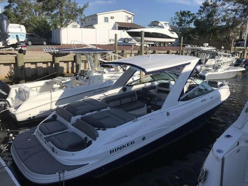 Slide: The Image of 2020 Rinker 29QX BR boat docked at a marina with other boats. - 8