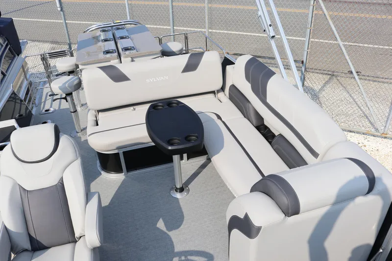 Slide: The Image of 2023 Sylvan L5 DLZ Bar pontoon boat with plush seating and table setup. - 17