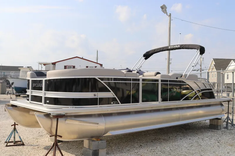 Slide: The Image of 2023 Sylvan L5 DLZ Bar pontoon boat on display in a marina setting. - 21