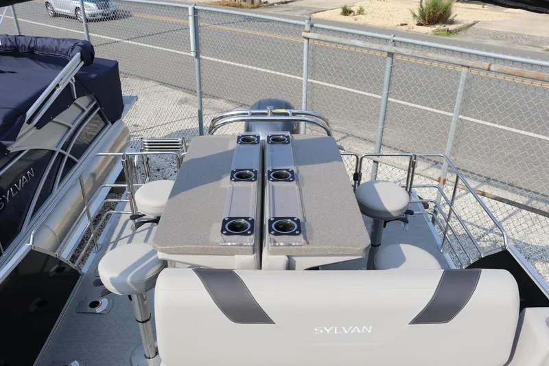 Slide: The Image of 2023 Sylvan L5 DLZ Bar pontoon boat with seating and table setup. - 6