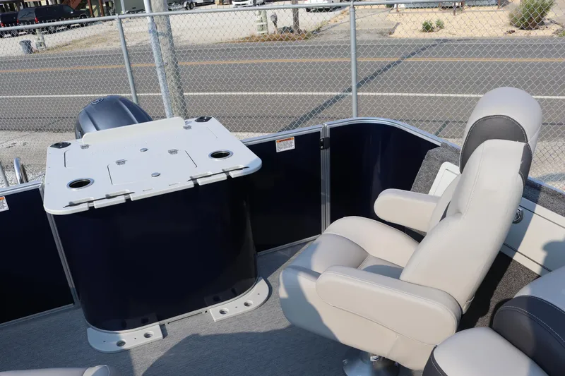 Slide: The Image of 2023 Sylvan L3 Party Fish boat interior with seating and table, near a chain-link fence. - 7