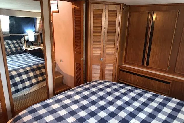 Slide: The Image of 1987 Sea Ray 410 Aft Cabin interior with checkered bedding and wooden cabinetry. - 23