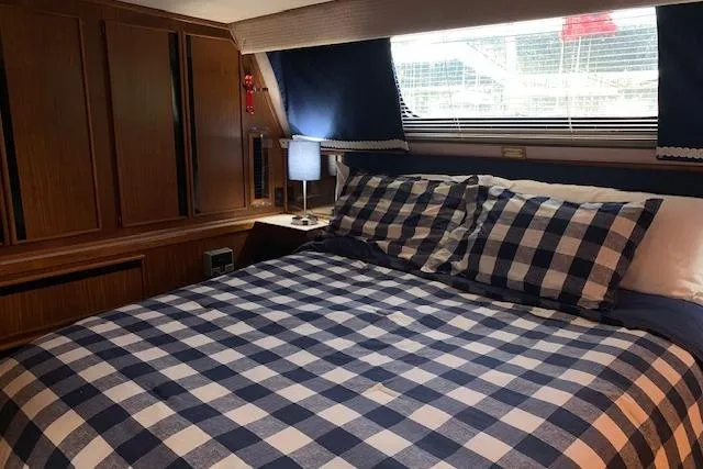 Slide: The Image of Cozy cabin interior of 1987 Sea Ray 410 Aft Cabin with checkered bedding. - 24