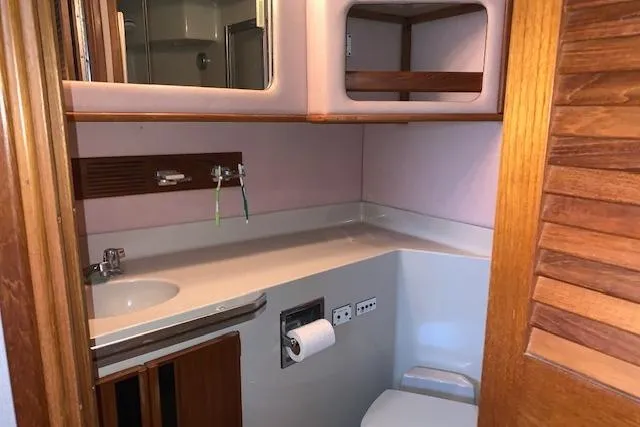 Slide: The Image of 1987 Sea Ray 410 Aft Cabin bathroom with sink, mirror, and storage shelves. - 25