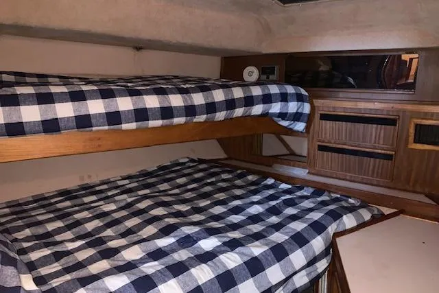Slide: The Image of 1987 Sea Ray 410 Aft Cabin interior with bunk beds and checkered bedding. - 29