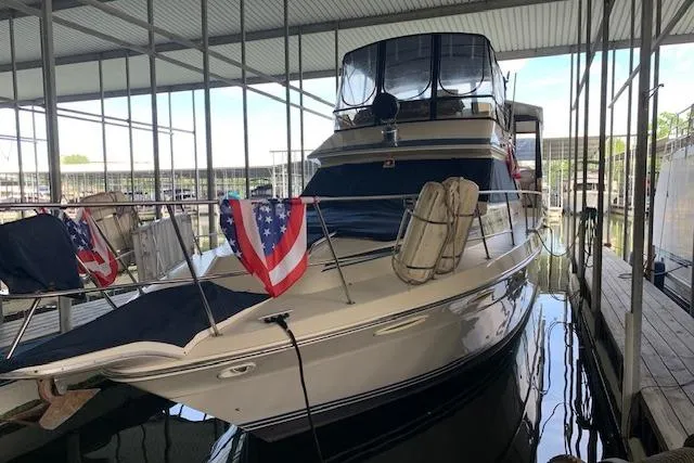 Slide: The Image of 1987 Sea Ray 410 Aft Cabin yacht docked under a covered marina with patriotic flags. - 4