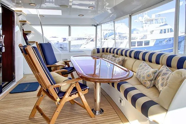Slide: The Image of Luxurious seating area on a yacht with a wooden table and cushioned benches, surrounded by windows. - 19