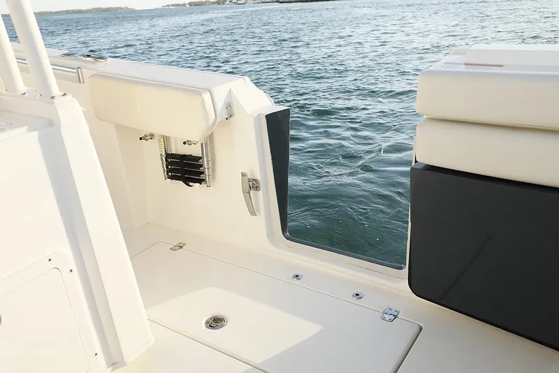 Slide: The Image of 2024 Cobia 301 CC boat interior with open side door, near water. - 11