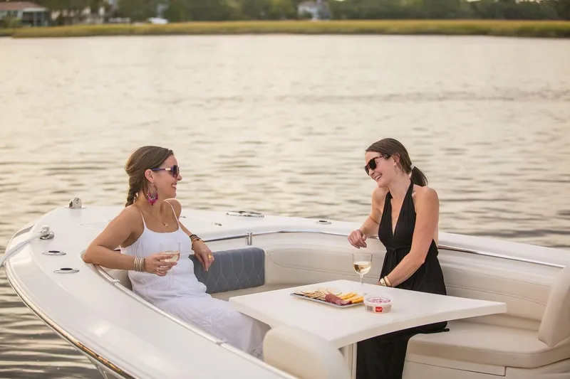 Slide: The Image of Two women enjoying wine on a 2024 Cobia 301 CC boat. - 12