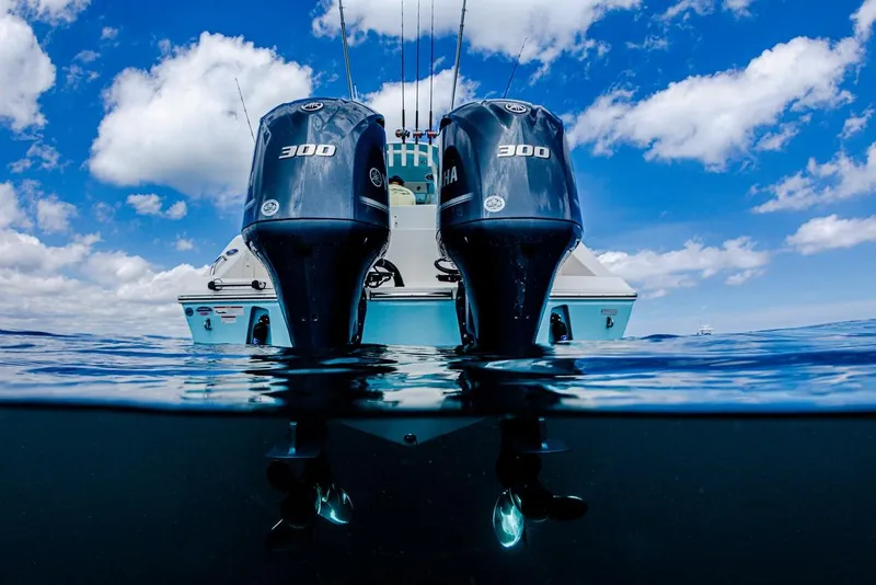Slide: The Image of 2024 Cobia 301 CC boat with twin 300 horsepower engines on open water. - 14
