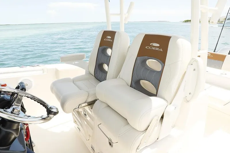 Slide: The Image of 2024 Cobia 301 CC boat with luxurious dual captain's chairs on a sunny day. - 8
