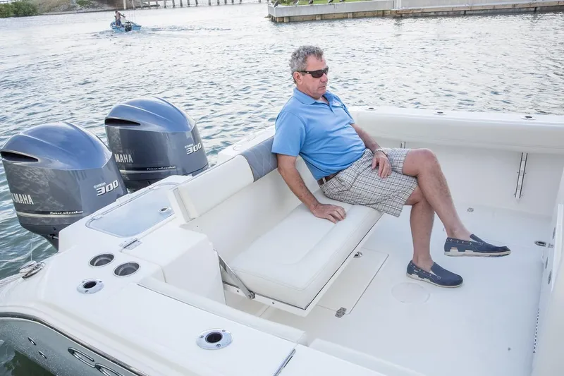 Slide: The Image of Man relaxing on a 2024 Cobia 320 CC boat with twin Yamaha 300 engines. - 13