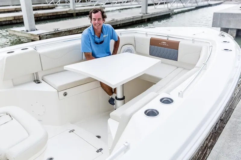 Slide: The Image of 2024 Cobia 320 CC boat with seating and table at the dock. - 6