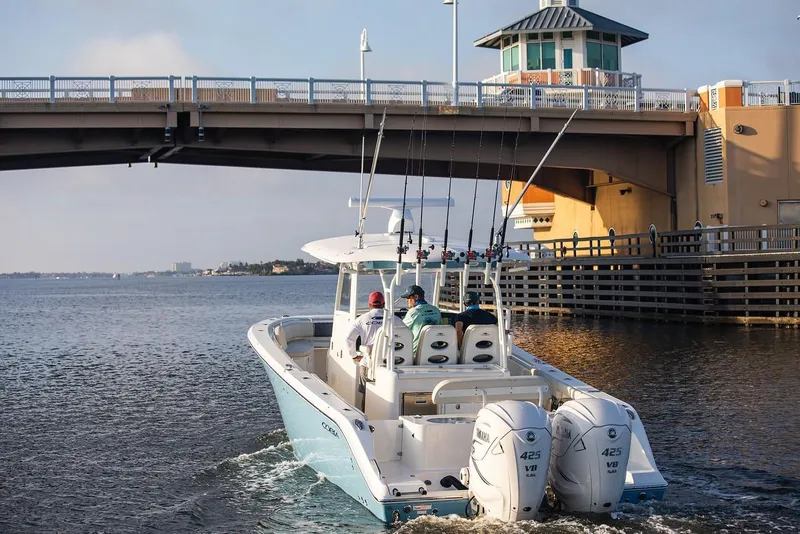The Image of 2024 Cobia 350 CC boat cruising under a bridge with fishing rods. - 1