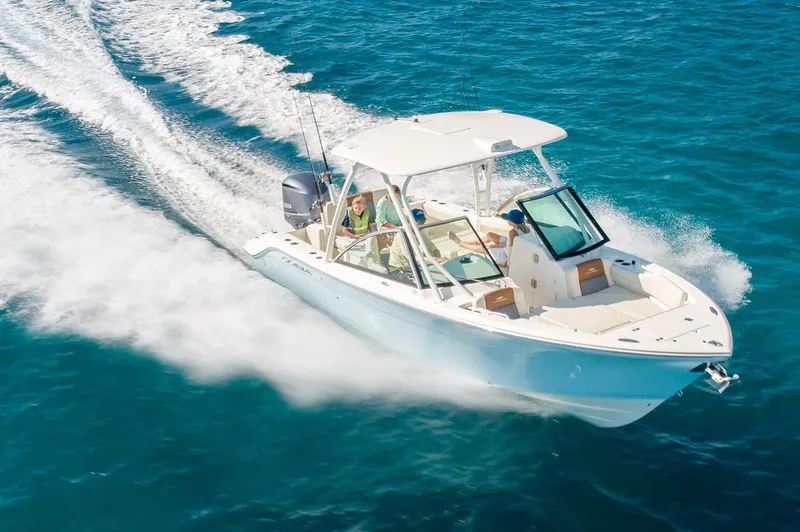 The Image of 2024 Cobia 240 Dual Console boat cruising on clear blue water. - 1