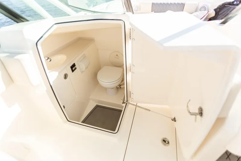 Slide: The Image of 2024 Cobia 240 Dual Console boat interior with a compact marine toilet. - 15
