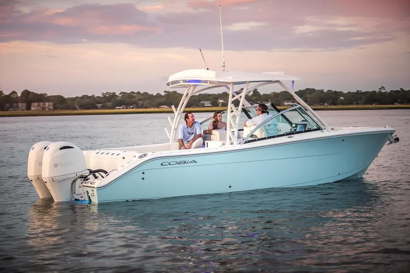 The Image of 2024 Cobia 280 Dual Console boat on calm water at sunset. - 0