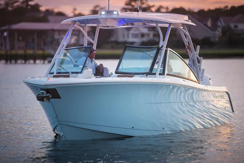 Slide: The Image of 2024 Cobia 280 Dual Console boat on water at sunset. - 15