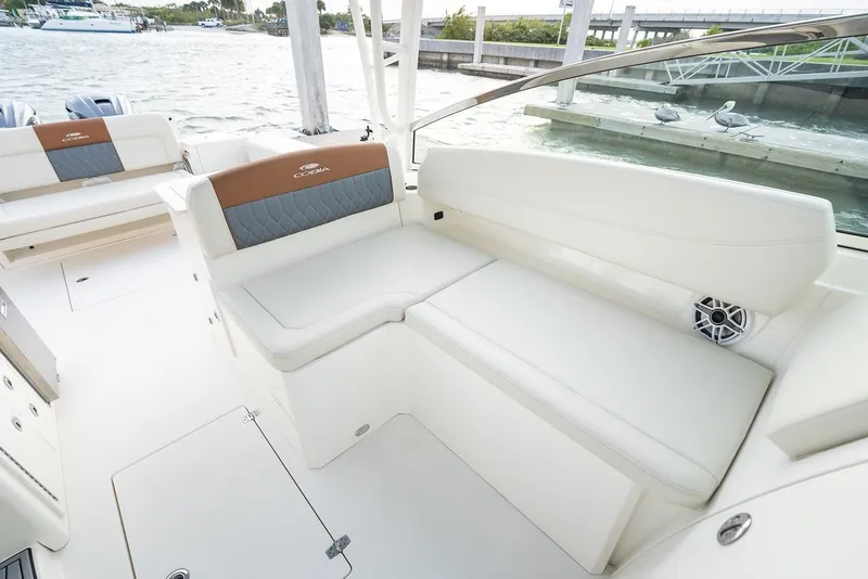 Slide: The Image of 2024 Cobia 330 Dual Console boat interior with white seating and waterfront view. - 11