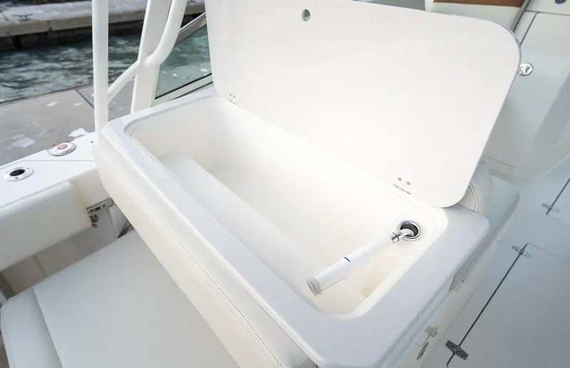 Slide: The Image of 2024 Cobia 330 Dual Console boat storage compartment with open lid. - 12