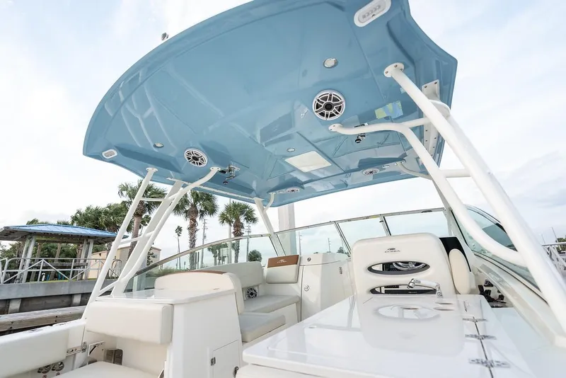 Slide: The Image of 2024 Cobia 330 Dual Console boat interior with blue hardtop and white seating. - 14