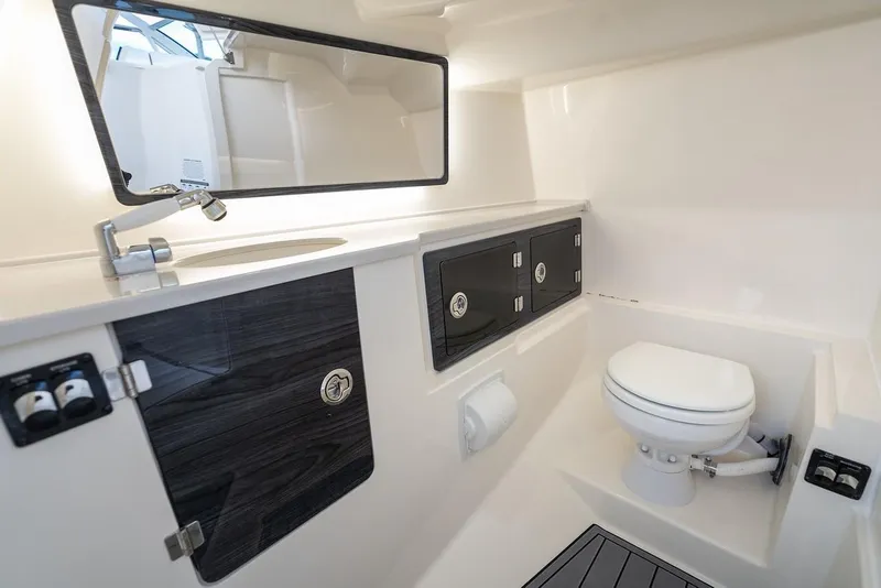 Slide: The Image of 2024 Cobia 330 Dual Console boat bathroom with modern fixtures and storage cabinets. - 17
