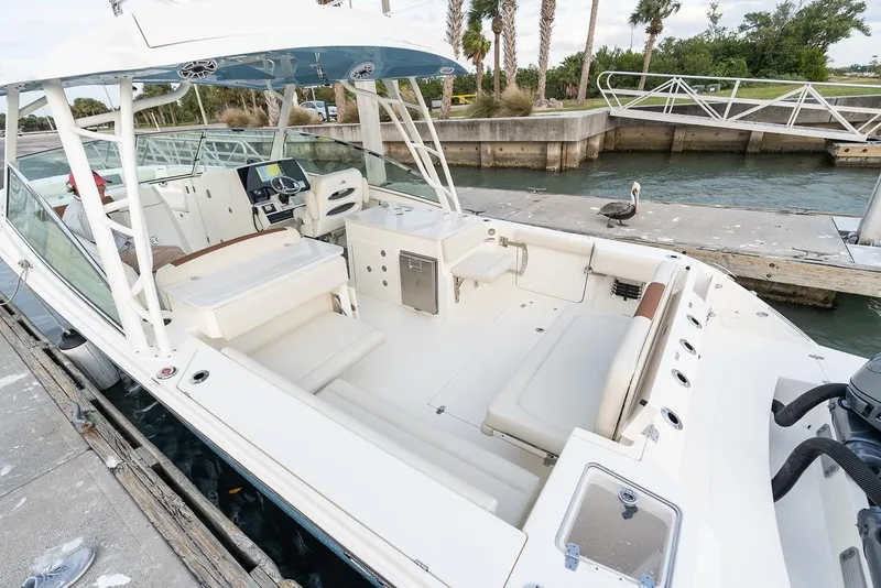 Slide: The Image of 2024 Cobia 330 Dual Console boat docked, showcasing spacious seating and modern design. - 8