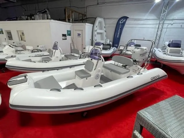 The Image of 2024 Grand Inflatables S420 boat displayed indoors on red carpet. - 0