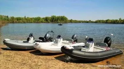 Slide: The Image of Three 2024 Grand Inflatables S420 boats on a sandy shore by a lake. - 11