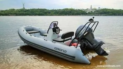 Slide: The Image of 2024 Grand Inflatables S420 boat on a calm lake with a scenic background. - 4