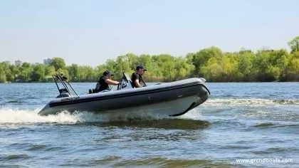 Slide: The Image of 2024 Grand Inflatables S420 boat cruising on a lake with two passengers. - 5