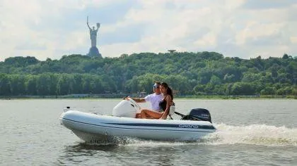 Slide: The Image of 2024 Grand Inflatables S330 boat cruising on a lake with a statue in the background. - 4