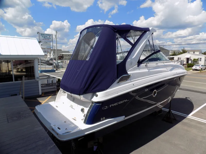 Slide: The Image of 2022 Regal 28 Express boat with blue canopy, parked outdoors under a cloudy sky. - 3