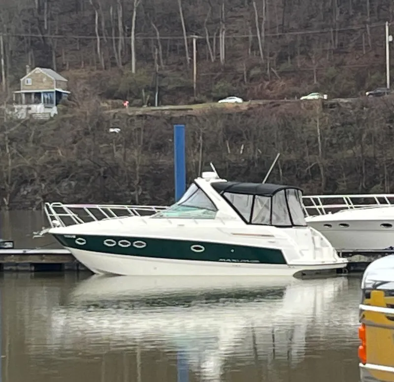 The Image of 2009 Maxum 3100 SE boat docked on a calm river with wooded background. - 0