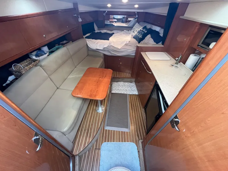 Slide: The Image of 2009 Maxum 3100 SE cabin interior with seating, table, kitchenette, and bed. - 35