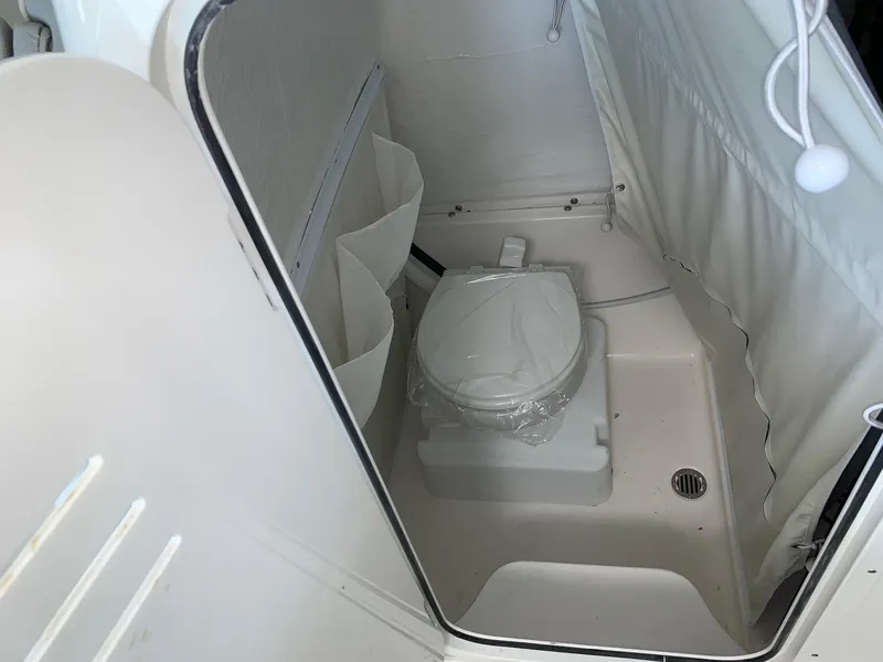 Slide: The Image of 2024 Key West 263 FS boat interior bathroom with toilet and storage compartments. - 12