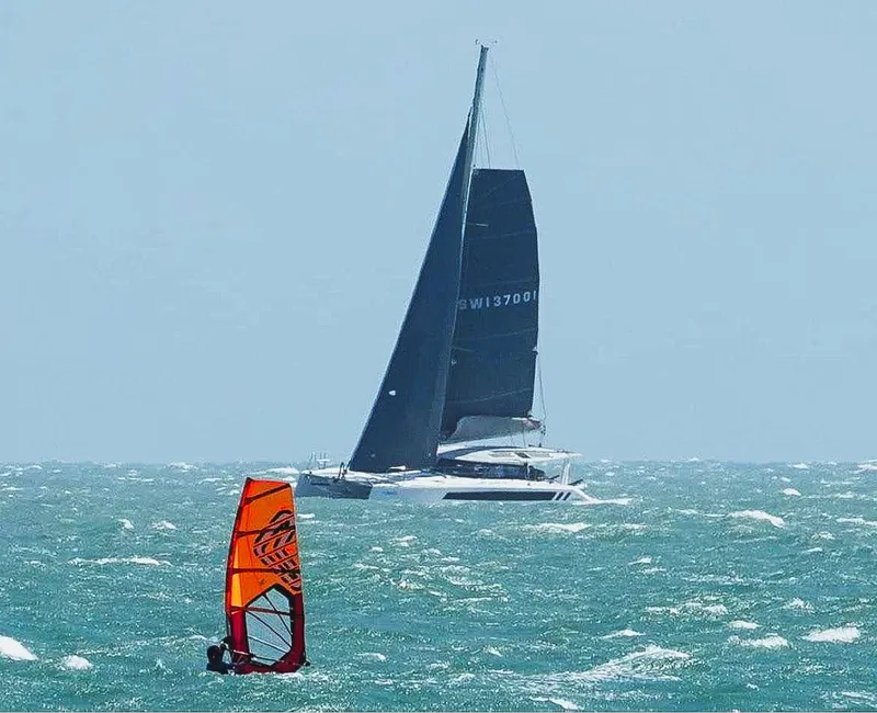 Slide: The Image of 2025 Seawind 1370 sailboat and windsurfer on the ocean. - 4