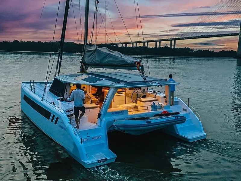 Slide: The Image of Seawind 1370 catamaran sailing at sunset near a bridge, 2025 model. - 7